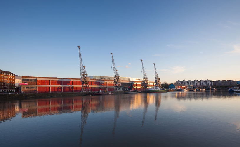 M Shed and three cranes reflected on the water at Bristol Harbourside