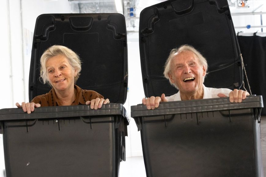 a man and a woman both in a wheelie bin each