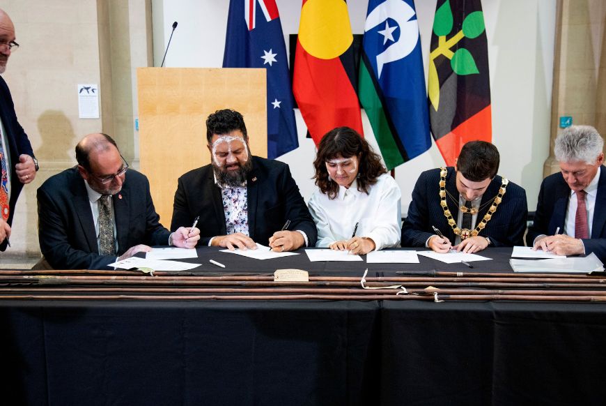 people sitting at adesk, signing papers
