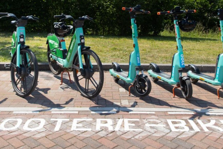 e-scooters and e-bikes parked on the pavement in a line