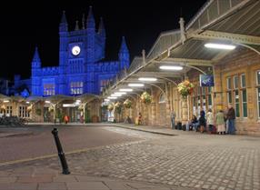 A group of people wait for the Airport Bus outside of Bristol Temple Meads Station