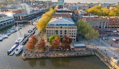 Aerial shot of the Arnolfini exterior, presumably via drone, showing its scenic location right on the harbourside. The shot is head-on and angled down