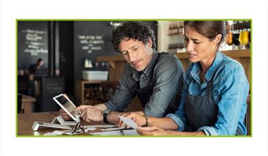 Two people talking and looking over receipts in a bar