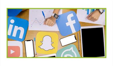 Photo from above a table looking down of phones, pens, tablets, hands, graphcs, and social media platform logos