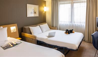 Novotel bedroom with a dog plushie on a couch bed