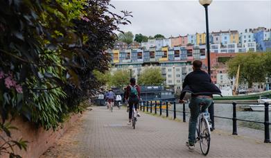 Bicyclers by the harbour looking at rows of coloured houses