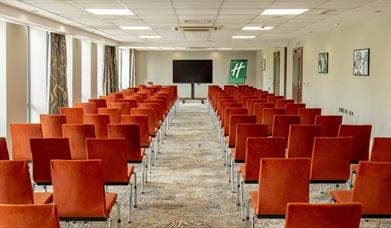 Conference room arranged theatre style seating with a central aisle as seen facing the presenter