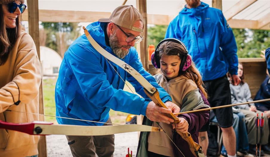 Instructor showing a girl how to do archery