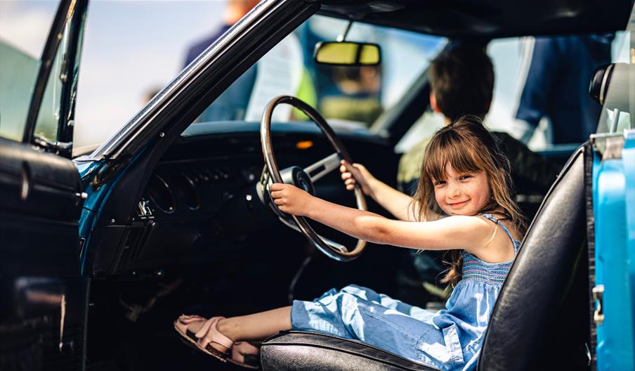 Child sitting in car at Haynes International Motor Museum