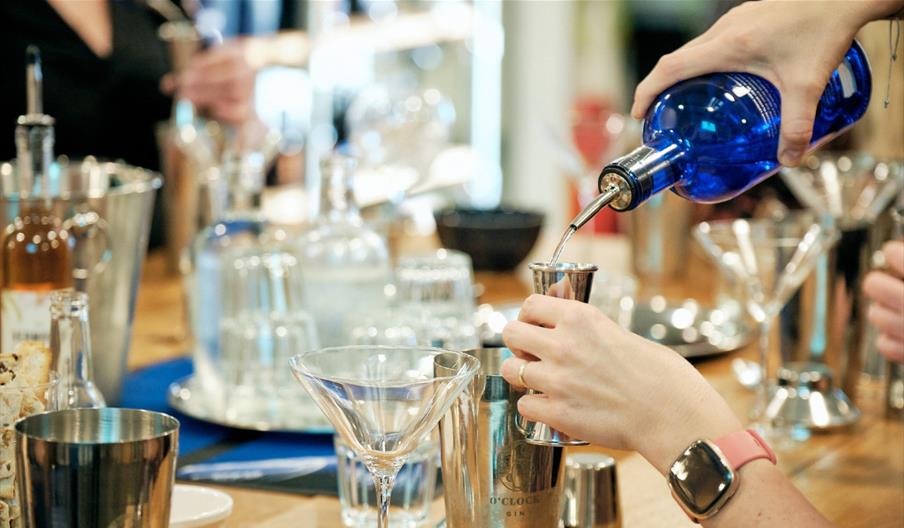 Person pouring gin and making a cocktail