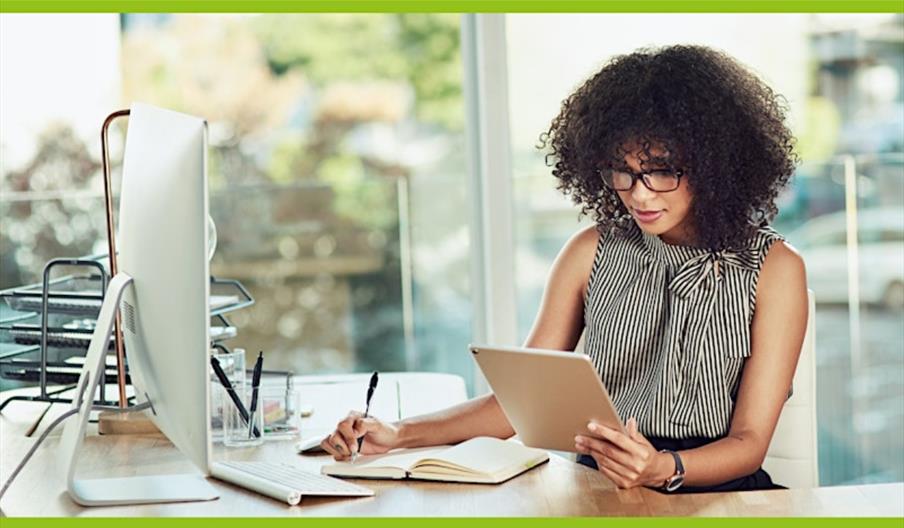 stock photo of someone writing in a journal and reading from a tablet