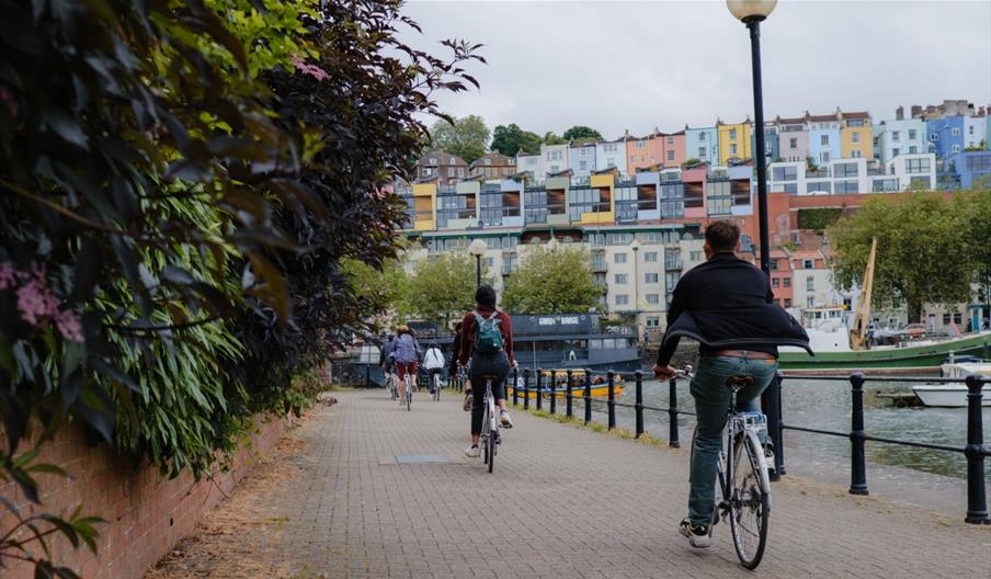 Bicyclers by the harbour looking at rows of coloured houses