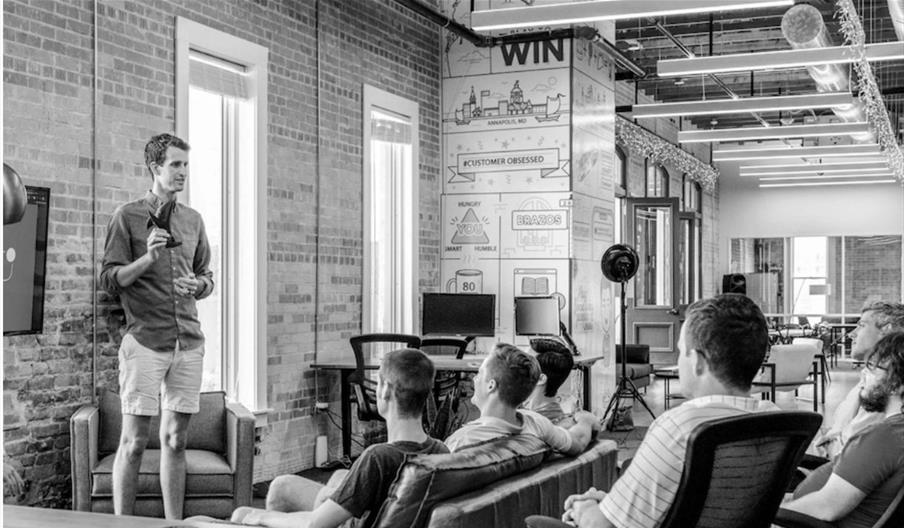 A man speaking to a room full of people sat down in a relaxed setting