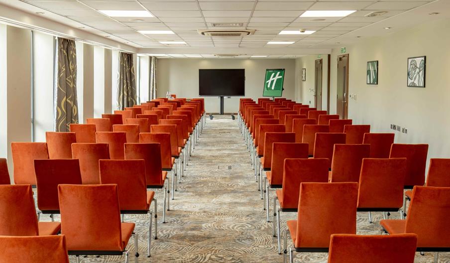 Conference room arranged theatre style seating with a central aisle as seen facing the presenter