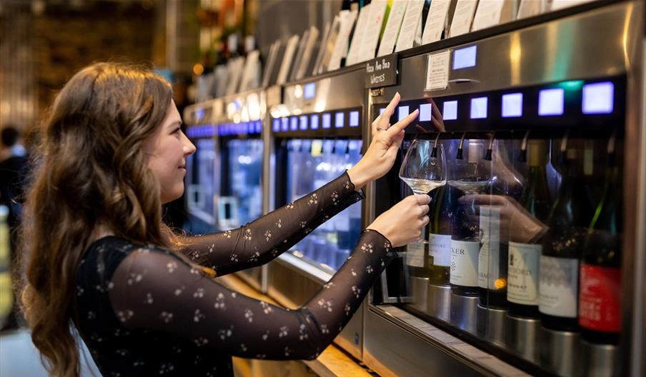 Person pouring wine from a machine
