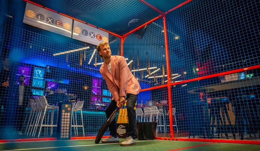 Sixes person batting in cage