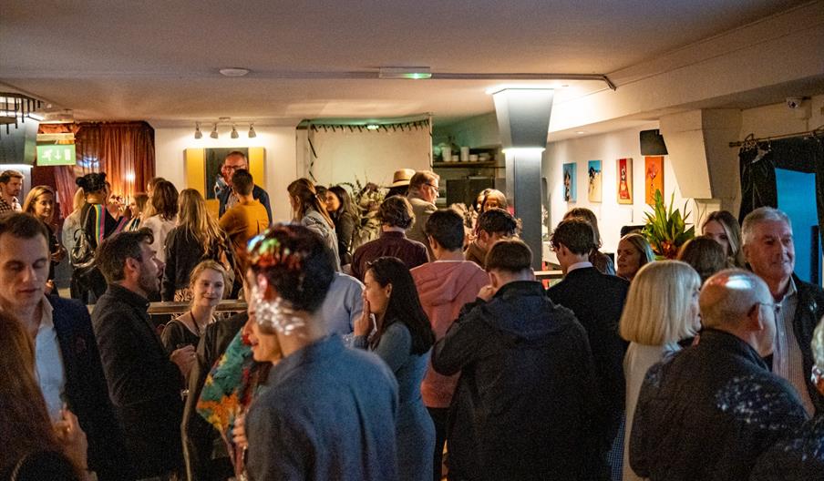 A group of people in a modern bar setting chatting and networking