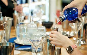 Person pouring gin and making a cocktail