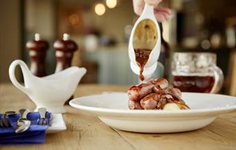 Gravy being poured over sausages
