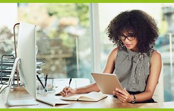 stock photo of someone writing in a journal and reading from a tablet