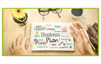 Stock photo of items on a table like someone's hands, glasses, and a page called Business Plan