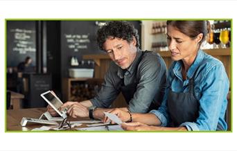 Two people talking and looking over receipts in a bar