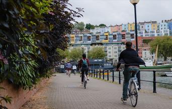 Bicyclers by the harbour looking at rows of coloured houses