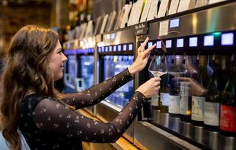 Person pouring wine from a machine