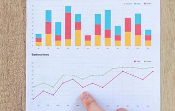 Hand pointing at charts and graphs.