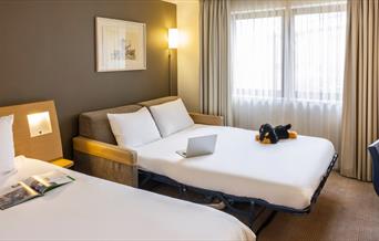 Novotel bedroom with a dog plushie on a couch bed