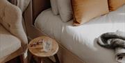 A circular side table between a bed and armchair in a hotel bedroom
