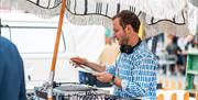 A man holding a vinyl behind a turntable under a brolly
