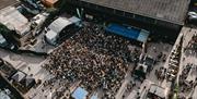 An aerial view of a large crowd gathered in front of an outdoor stage