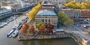 Aerial shot of the Arnolfini exterior, presumably via drone, showing its scenic location right on the harbourside. The shot is head-on and angled down