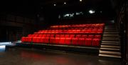 Interior shot of the black box theatre looking at the rows of seating, as seen from stage right, the right side of the venue from the perspective of t