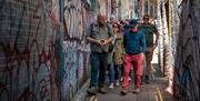 Luke guiding his tour through an alley covered in graffiti and sharing his knowledge with them.