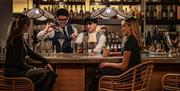Bartenders mixing cocktails for people at the bar