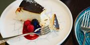 A slice of chocolate covered cheesecake with berries and a sauce