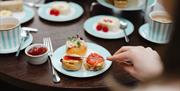 Hand applying jam to a scone