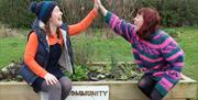 Two people giving each other a high five on top of a community garden box