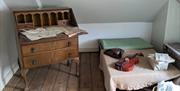 Bedroom, with bed, chest of drawers, and various items laid on the bed