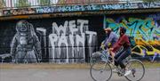 Bicyclers passing graffiti