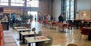 Flightline cafe and bar at Aerospace Bristol. Tables and chairs set up in a coffee shop style interior