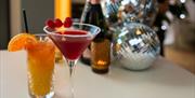 Festive cocktails, bottle of champagne and festive decorations