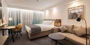 Interior shot of a room at Holiday Inn Bristol airport including bed, several tables, a chair, a tv, and a sofa.