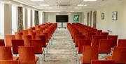 Conference room arranged theatre style seating with a central aisle as seen facing the presenter