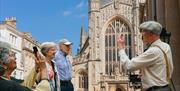 Photo of a tour guide talking to the tour group with the Bath Abbey in the backdrop