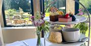 A three-tiered afternoon tea display overlooking a garden view