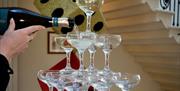 Hand pouring champagne into stacked glasses