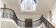 Staircase, balcony, and chandelier hanging from above